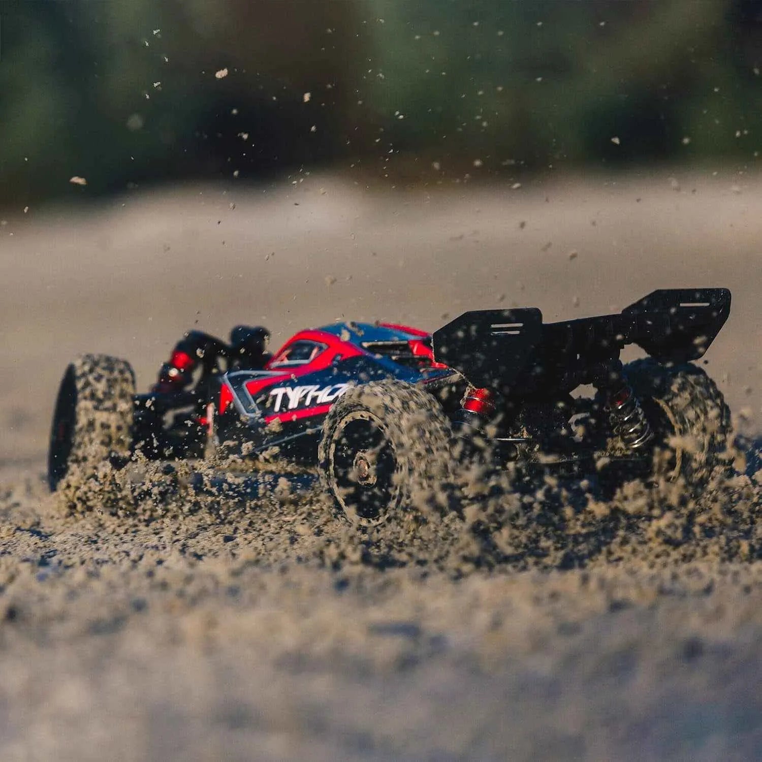 Model off-road buggy racing on a sandy surface with Tyre logo visible