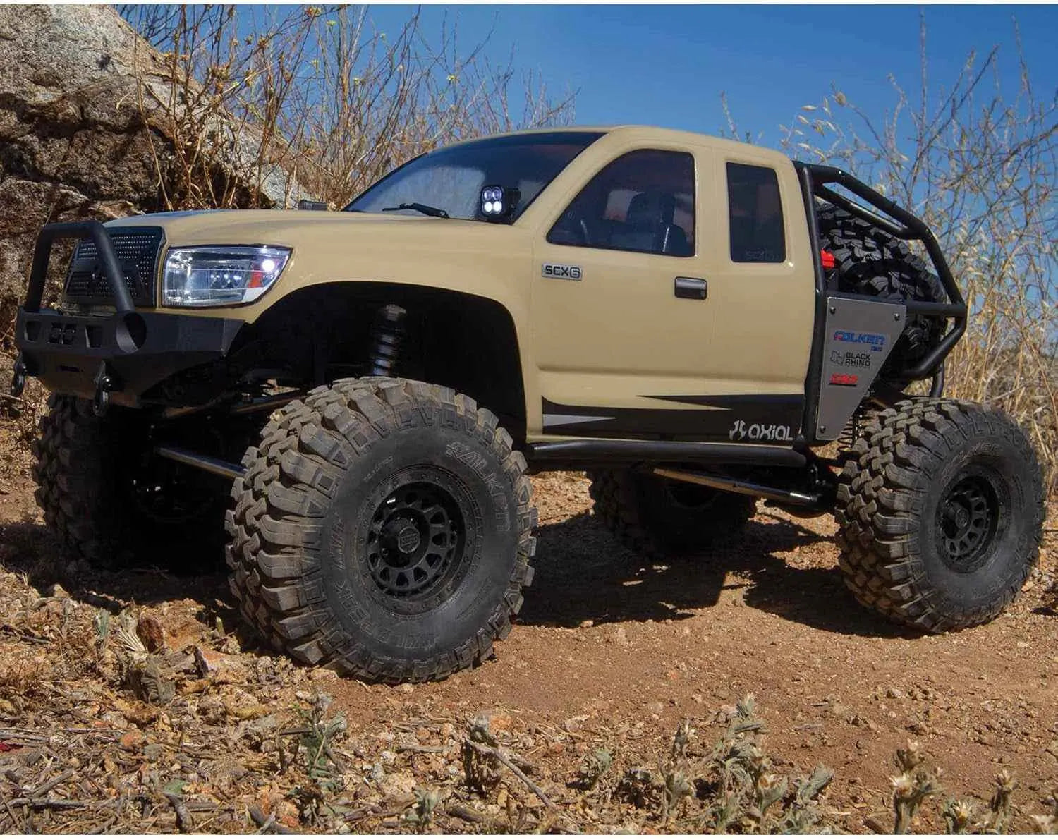 Beige off-road RC crawler with large tires on a rocky terrain