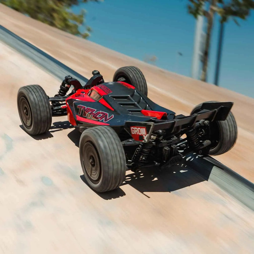 Black and red off-road buggy on a sandy track with clear blue sky.
