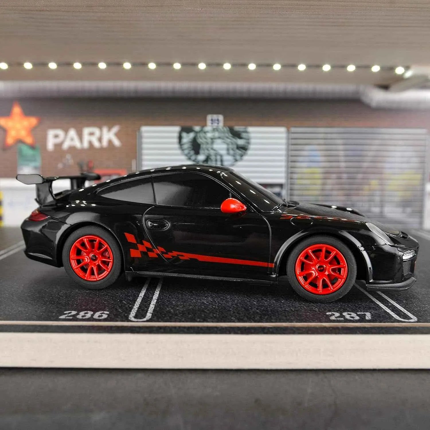 Black RC sports car with red wheels on a miniature parking lot