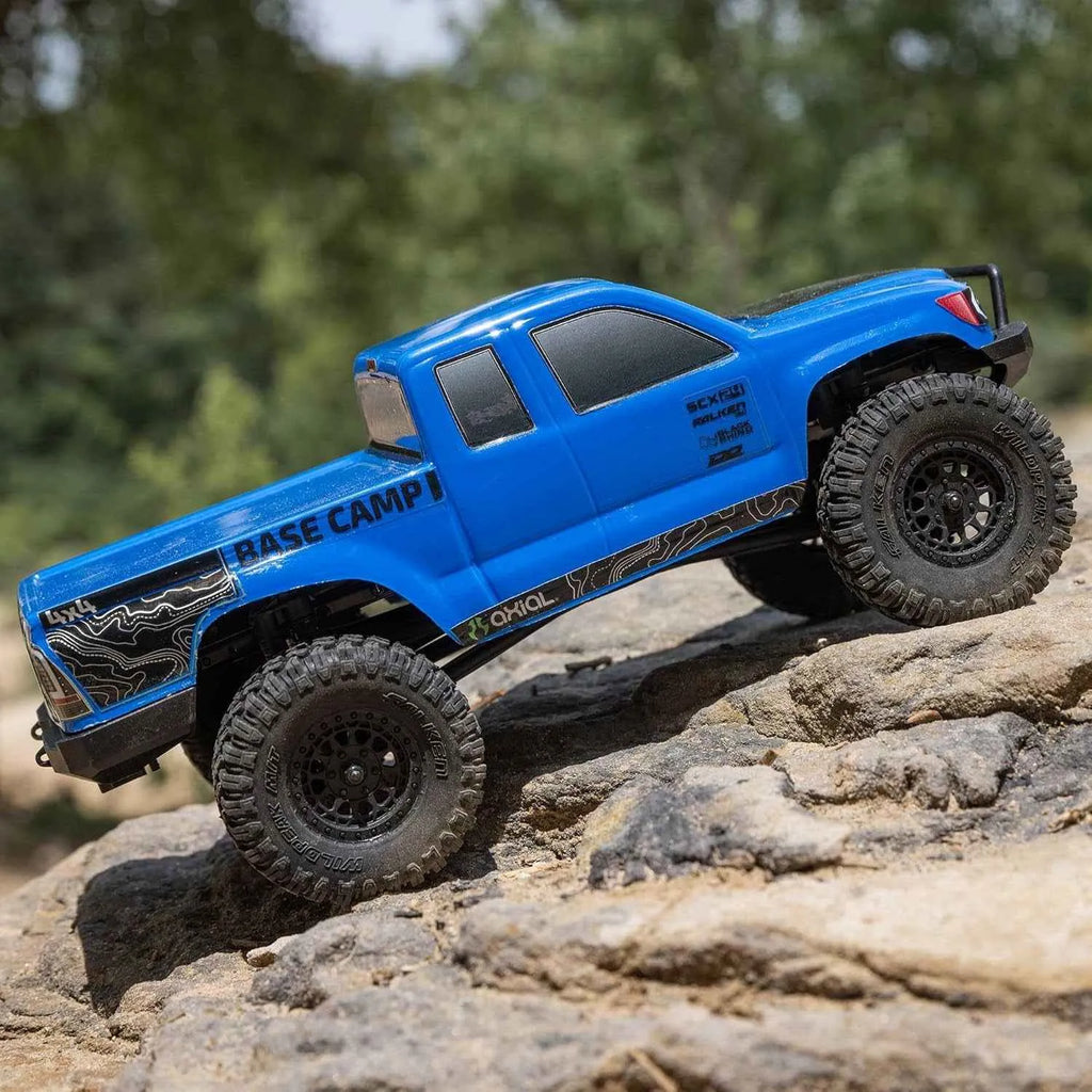 Blue off-road rc crawler on rocky terrain with trees in the background