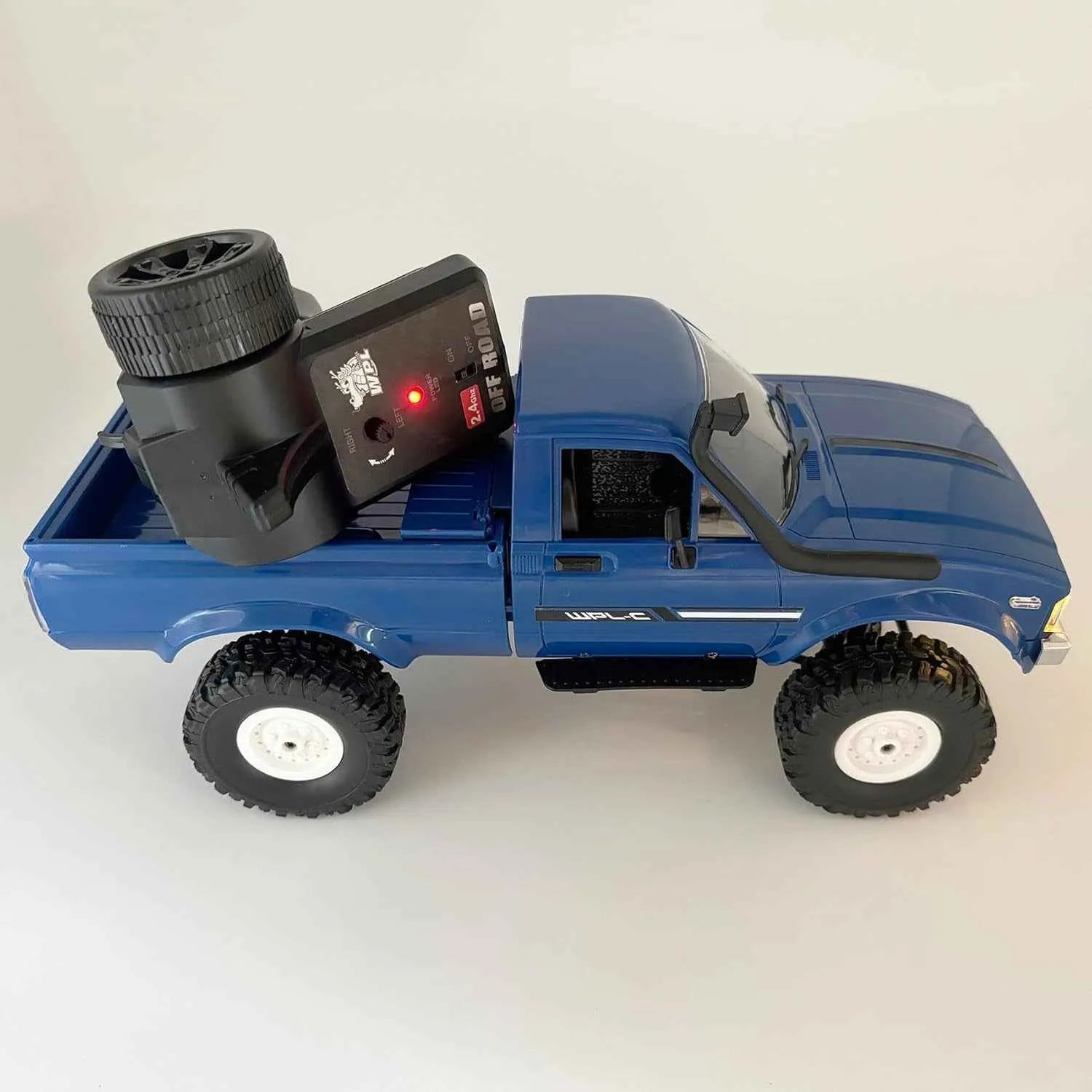 Blue RC crawler with remote control on a white background