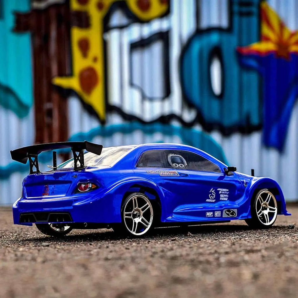 Blue rc drift car on a textured surface with a colorful mural in the background