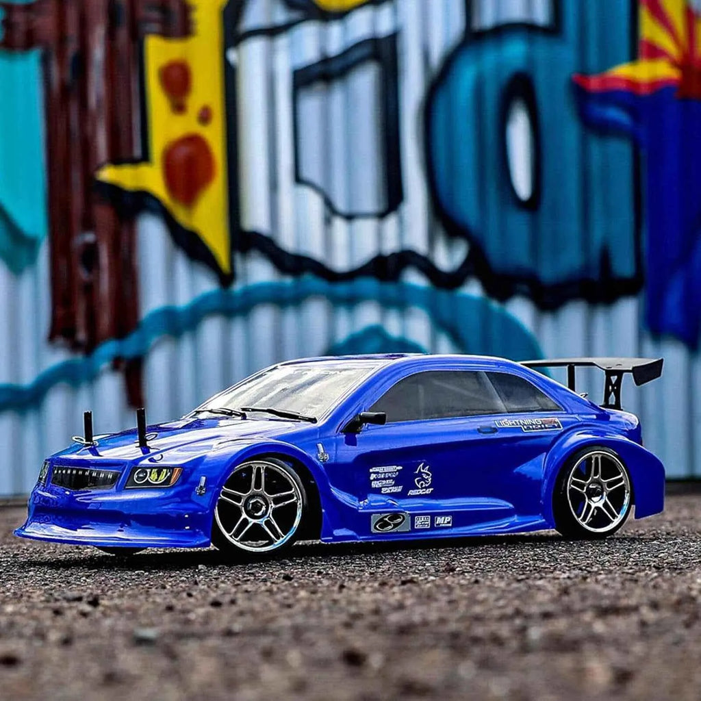Blue rc drift car on a textured surface with a colorful mural in the background
