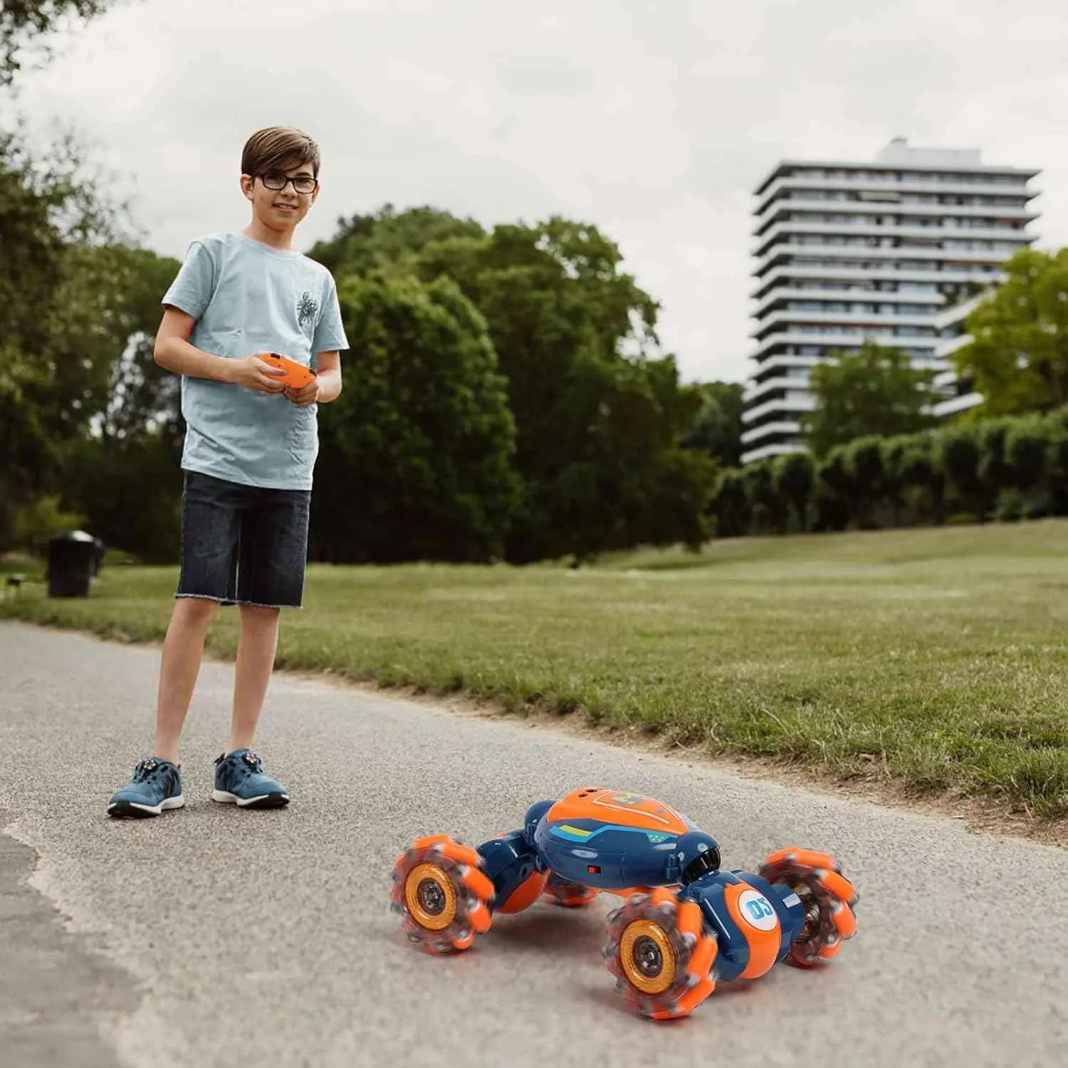 Child playing with remote control stunt car on a path in a park