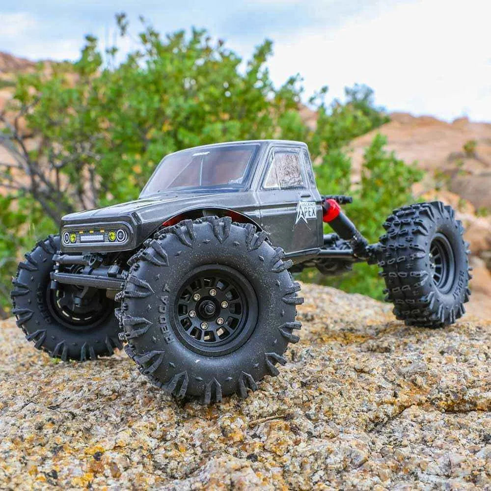 Model off-road crawler on rocky terrain with greenery in the background