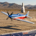 Model RC airplane in flight with desert landscape and checkered tower in the background