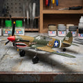 Model RC airplane on a workbench with paint cans and tools in the background