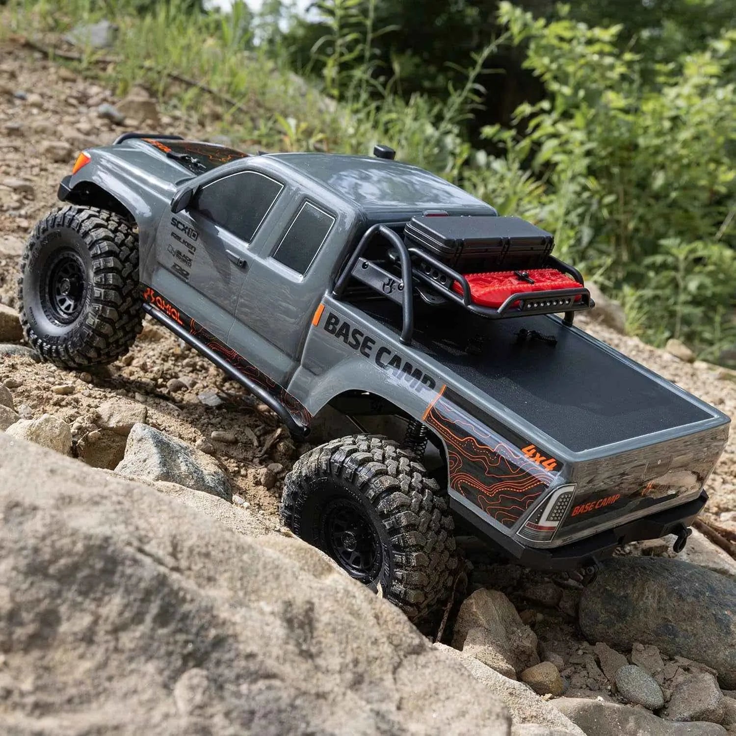 Model RC crawler on a rocky terrain with greenery in the background