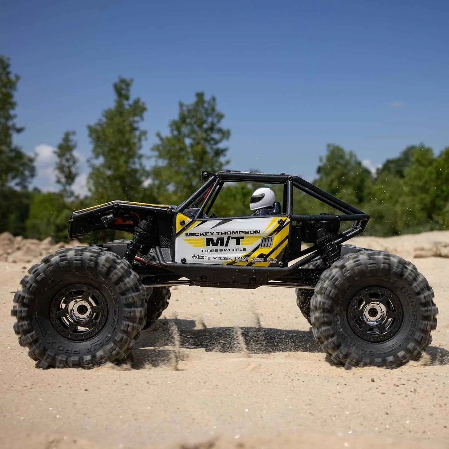 Off-road crawler on a sandy terrain with trees in the background