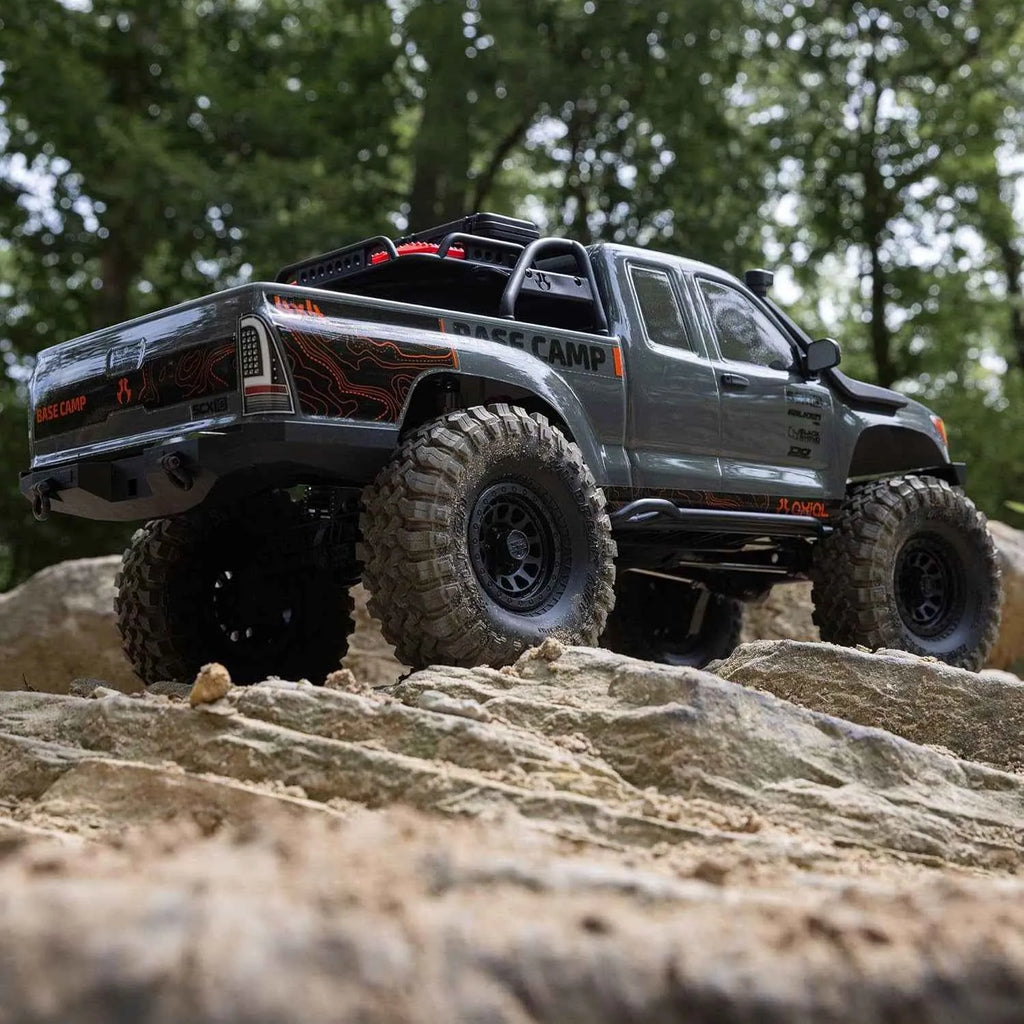 Off-road RC crawler climbing rocky terrain with trees in the background