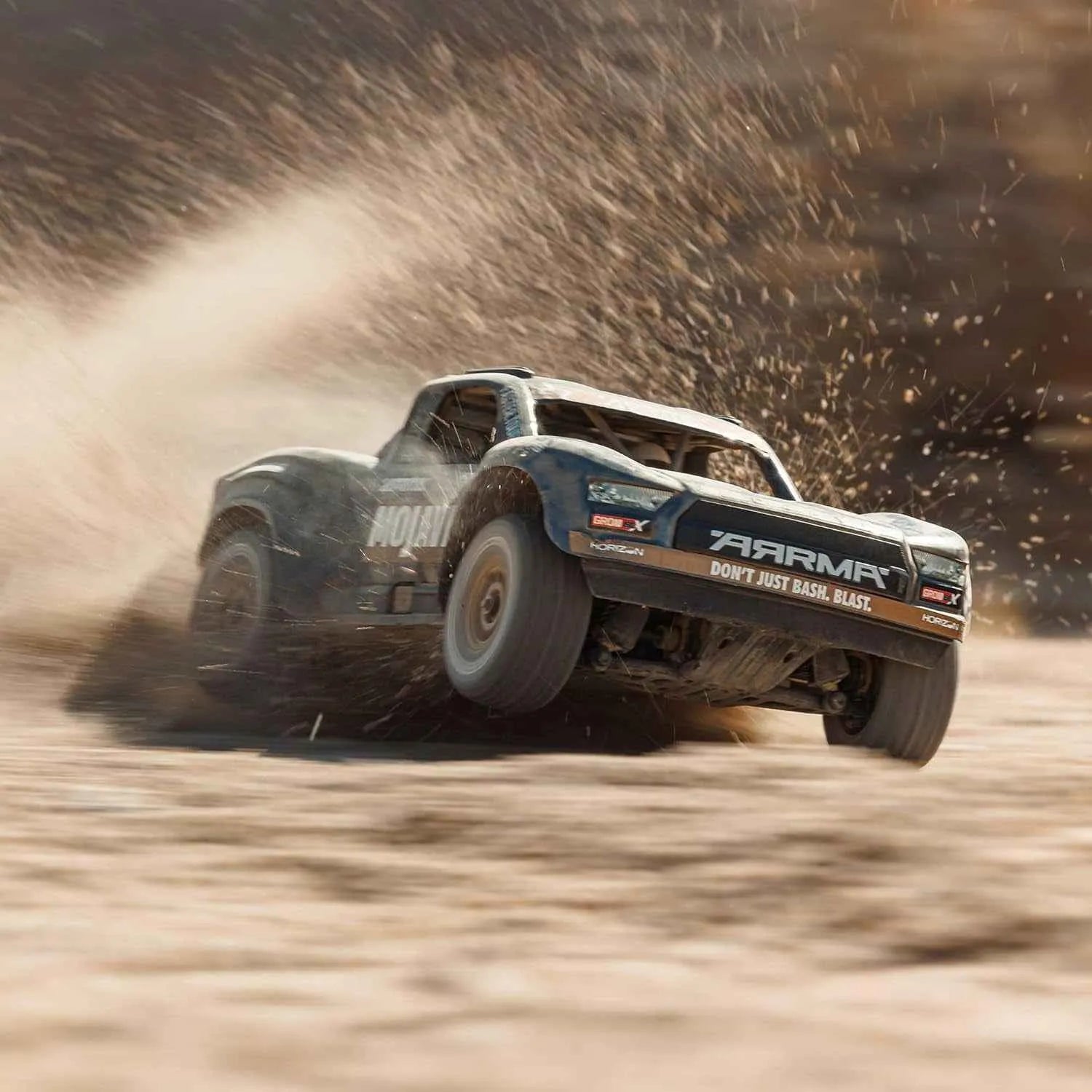 Off-road truck racing on a dirt track with dust and debris in the air