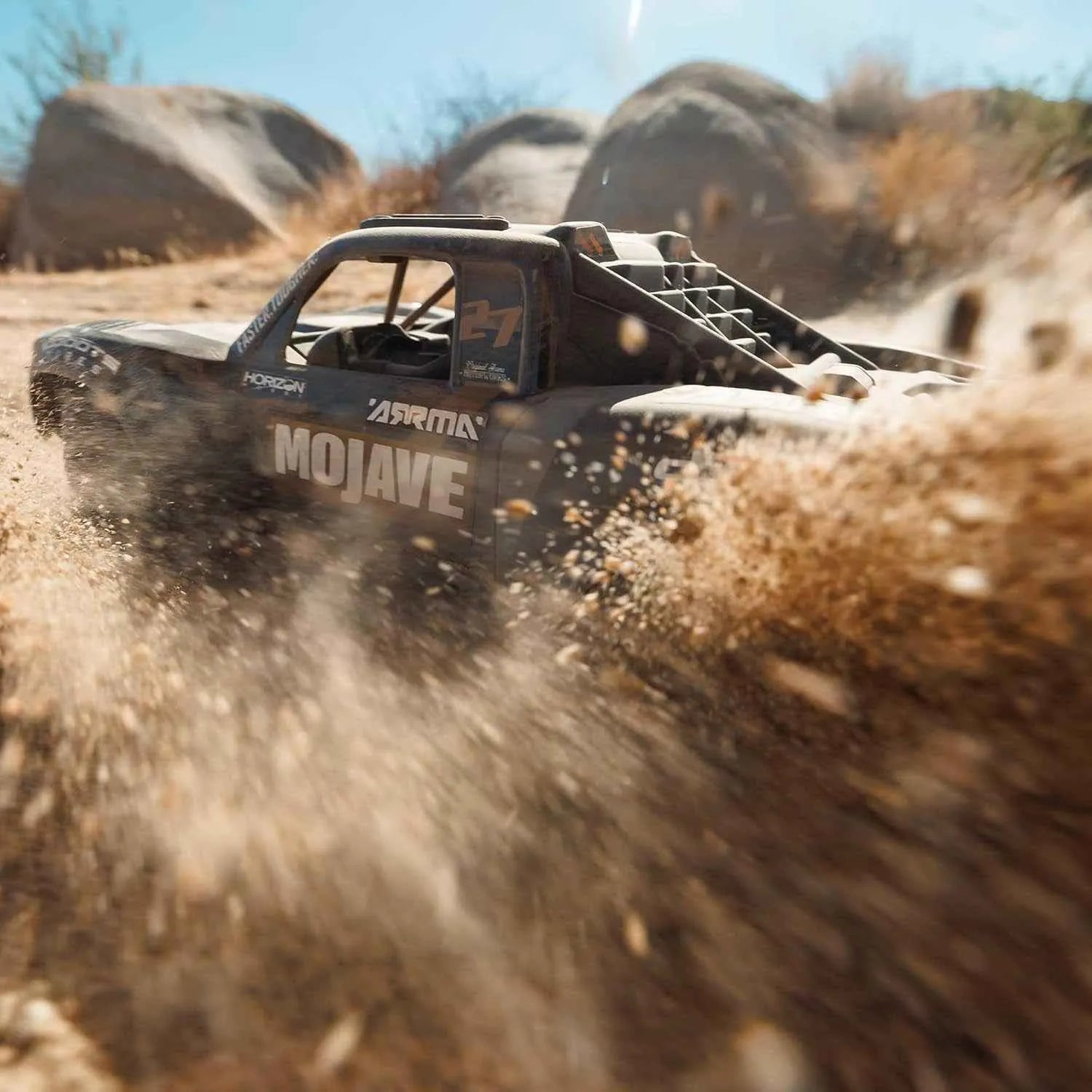 Off-road vehicle labeled 'Mojave' driving through a desert landscape with rocks and sand.