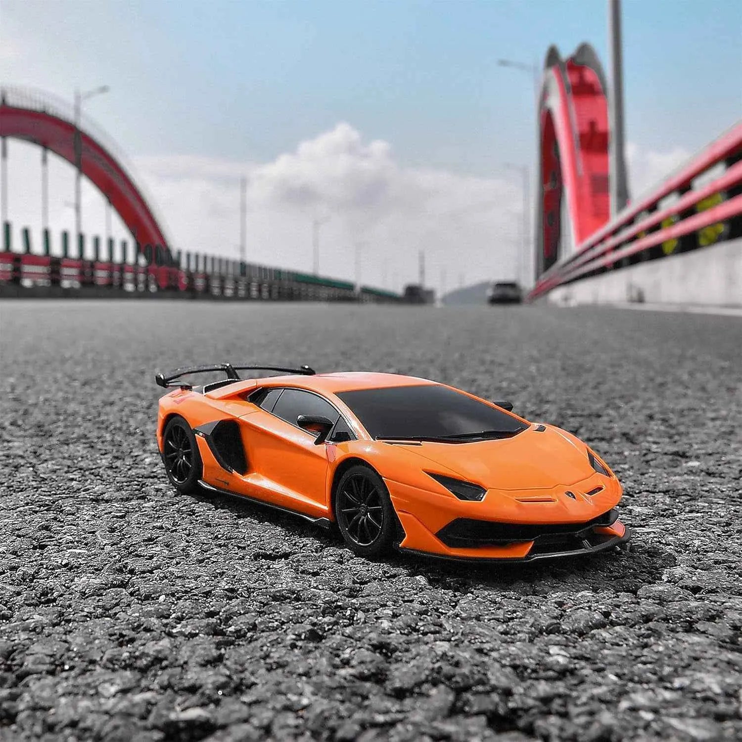 Orange sports car model on a road with a bridge in the background