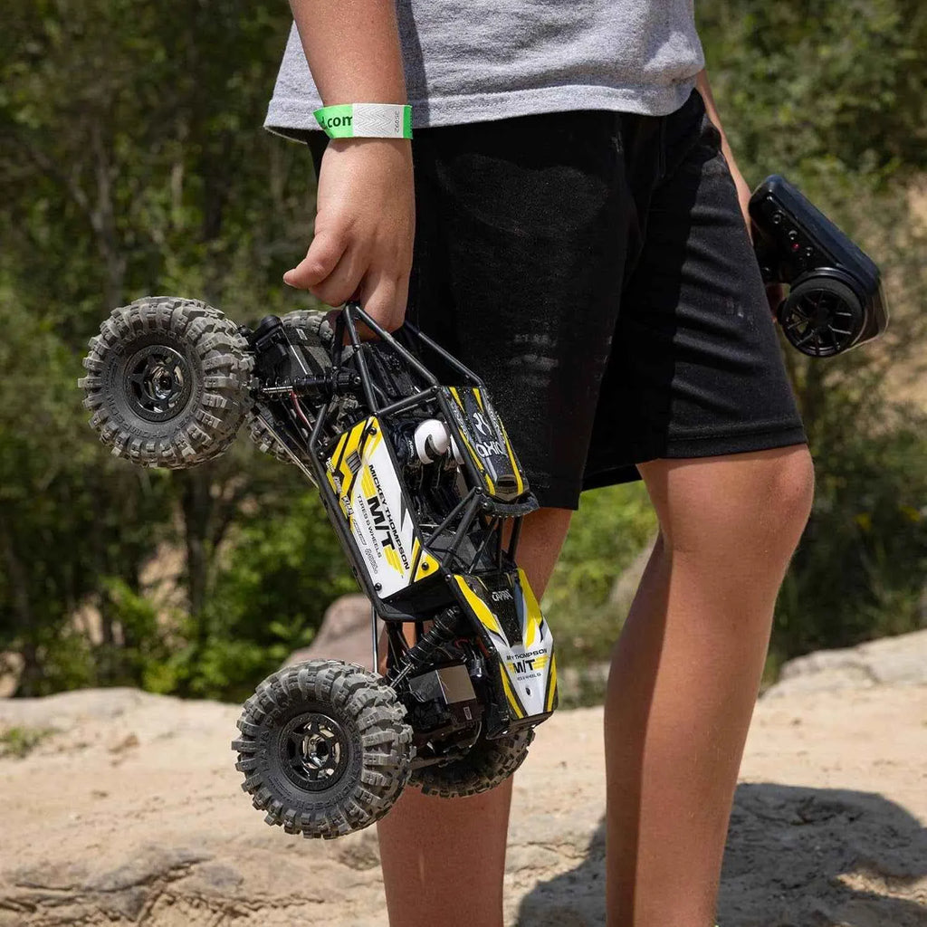 Person holding a remote control rc crawler outdoors with greenery in the background