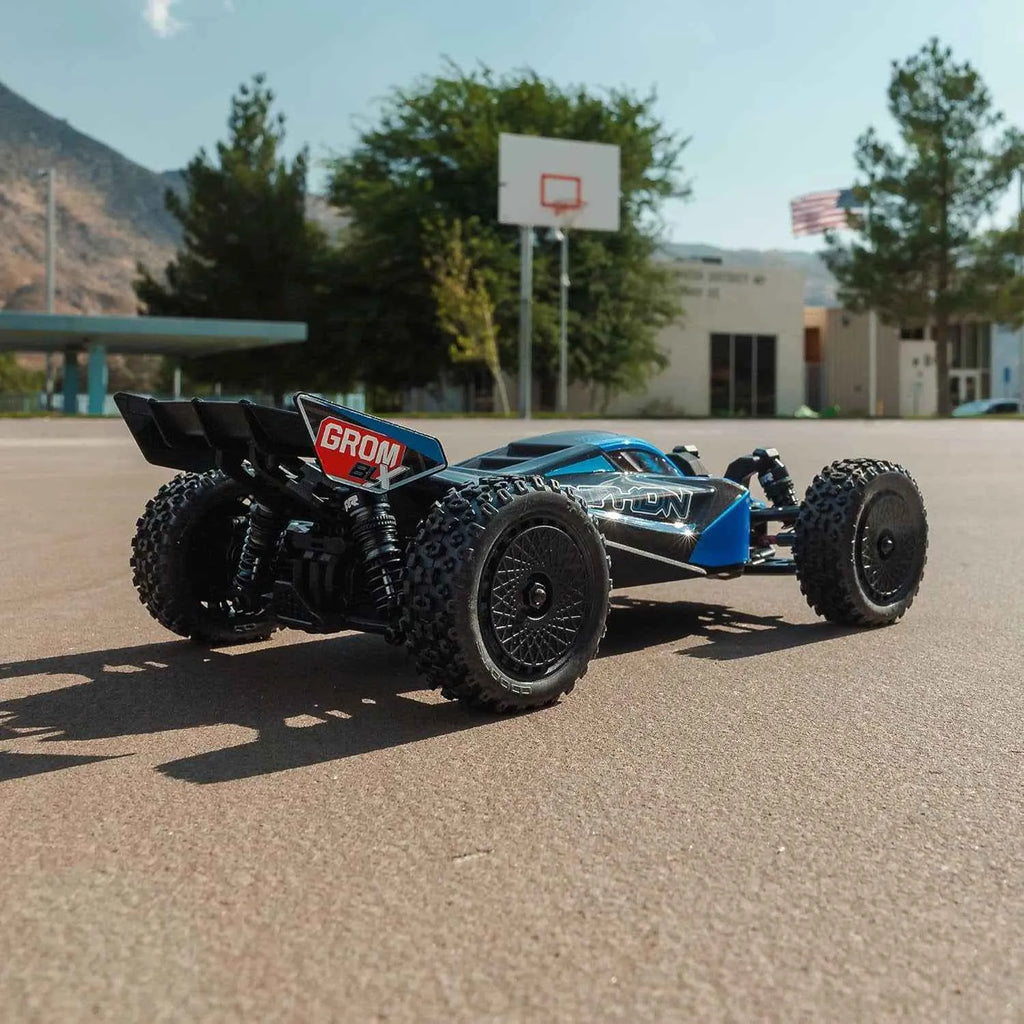 rc buggy car on a paved surface with a building and trees in the background.