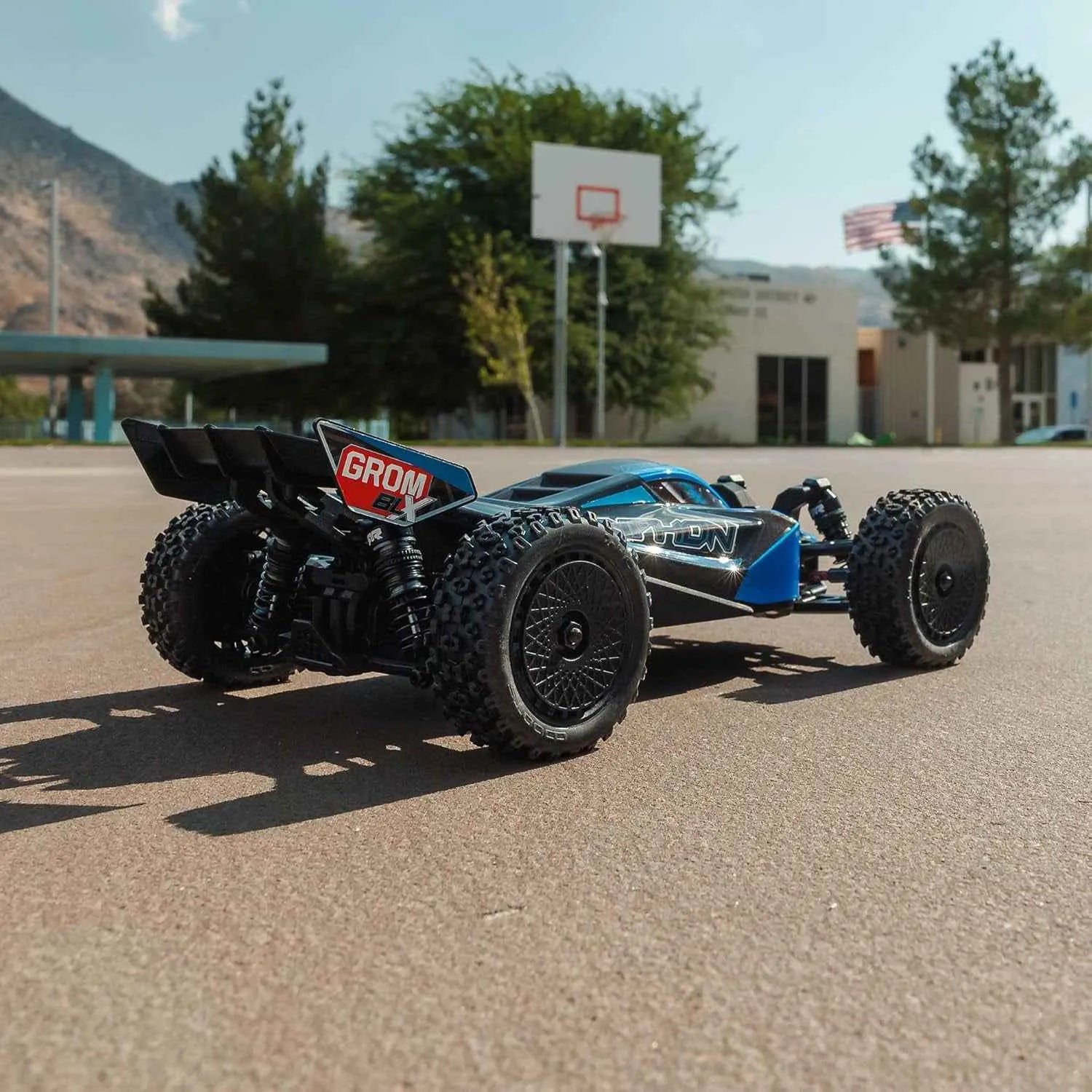 rc buggy car on a paved surface with a building and trees in the background.