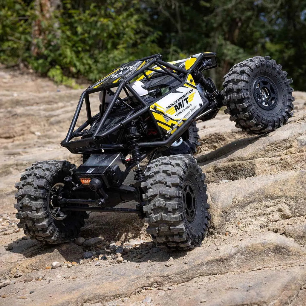 RC off-road crawler on a rocky surface with trees in the background