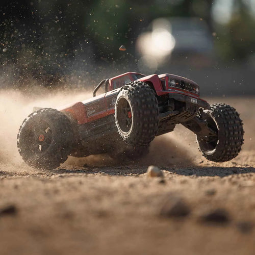 Red off-road RC stunt car racing on a dirt track with dust in the air
