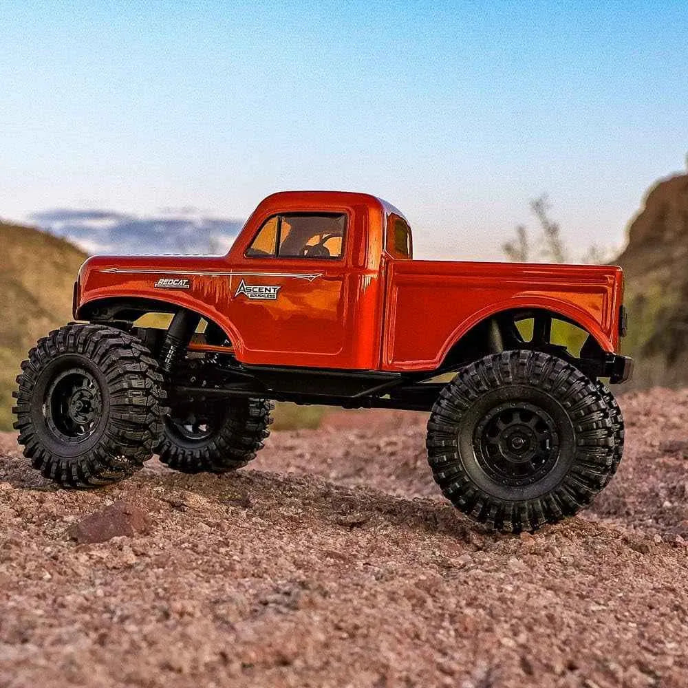 Red rc crawler truck with large wheels on a rocky terrain