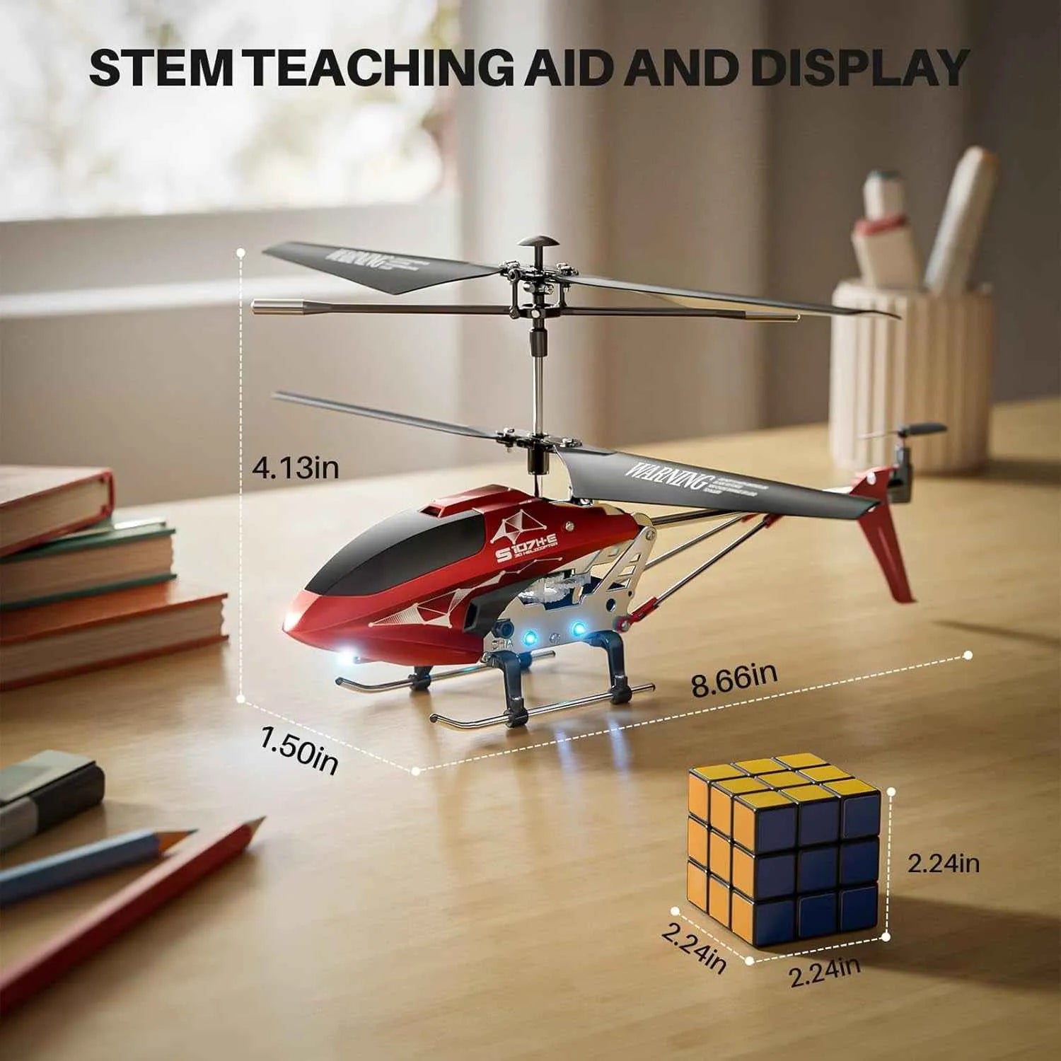 Red RC helicopter with dimensions labeled on a desk, used as a STEM teaching aid.