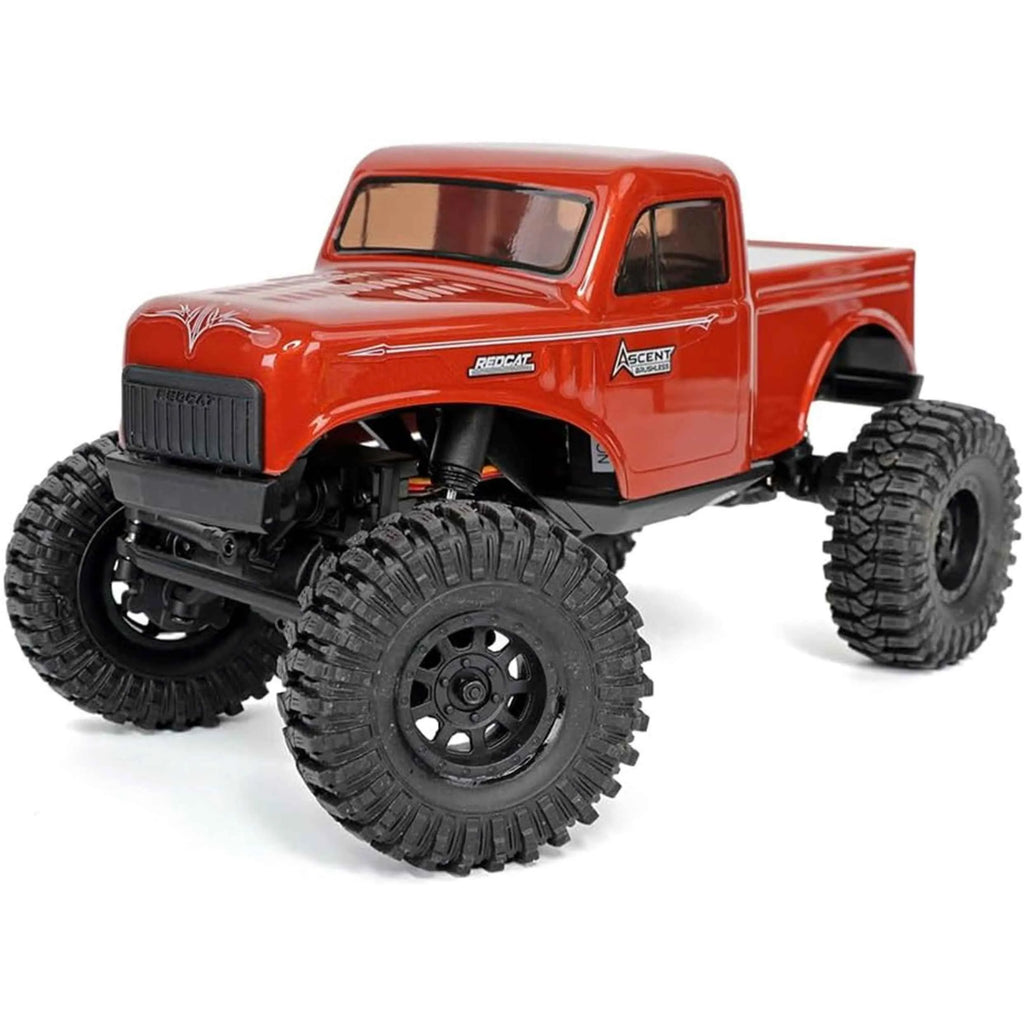Red RC rock crawler with large black tires on a white background