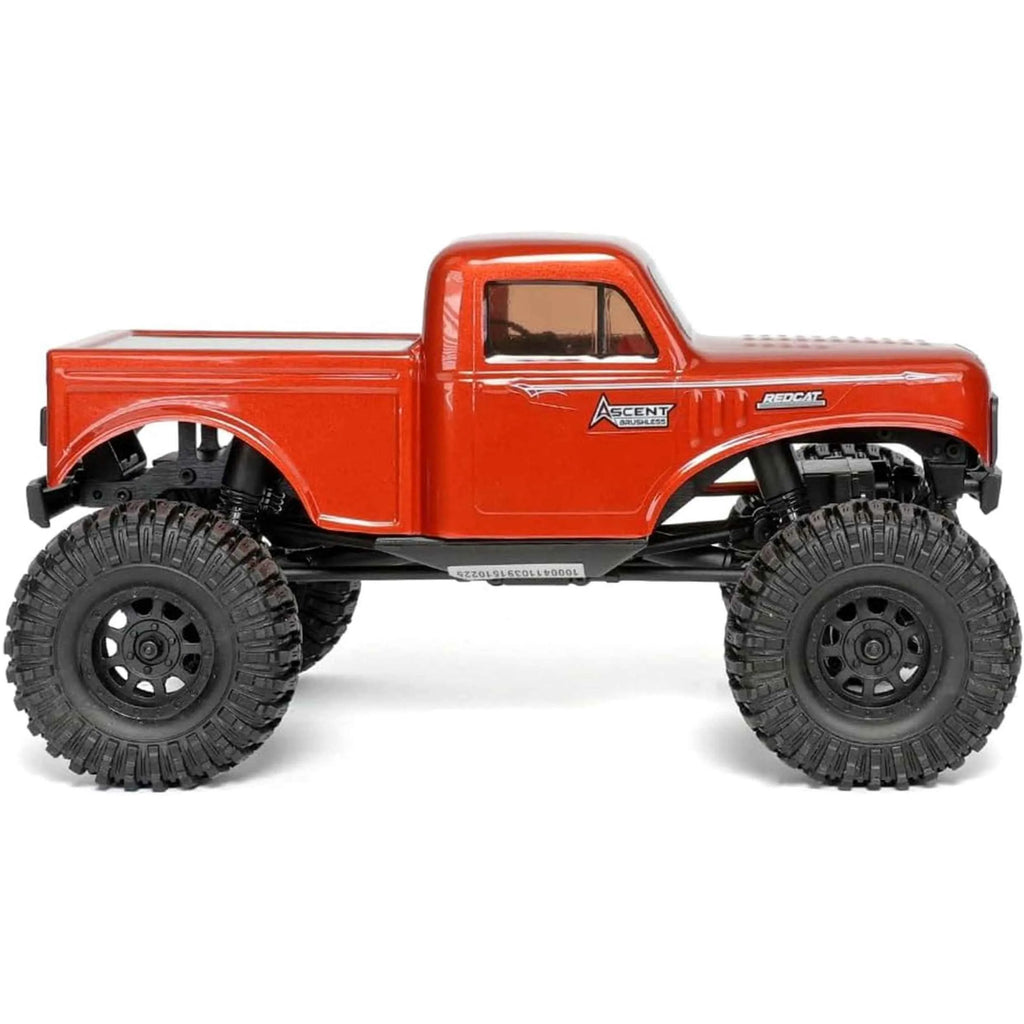 Red RC rock crawler with large black wheels on a white background
