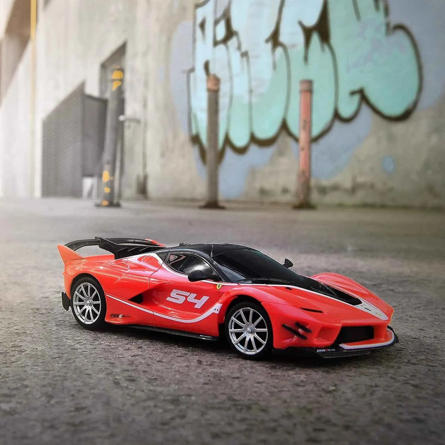 Red RC sports car with '54' on a textured surface with graffiti in the background