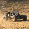Remote-controlled off-road monster truck with lights on a dirt surface