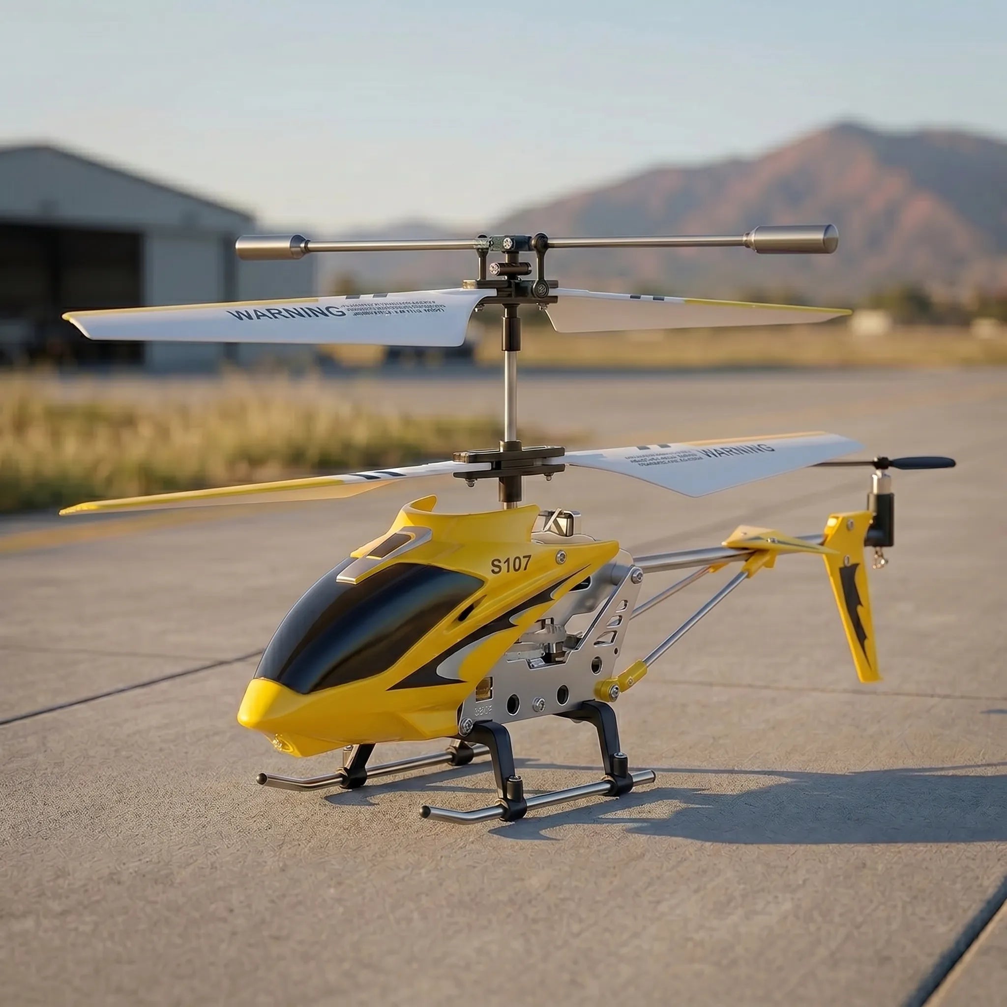Yellow and black RC helicopter on a tarmac with mountains in the background